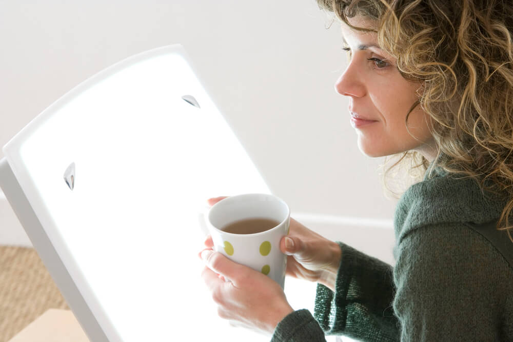 A woman using a sad lamp to overcome Seasonal Affective Disorder